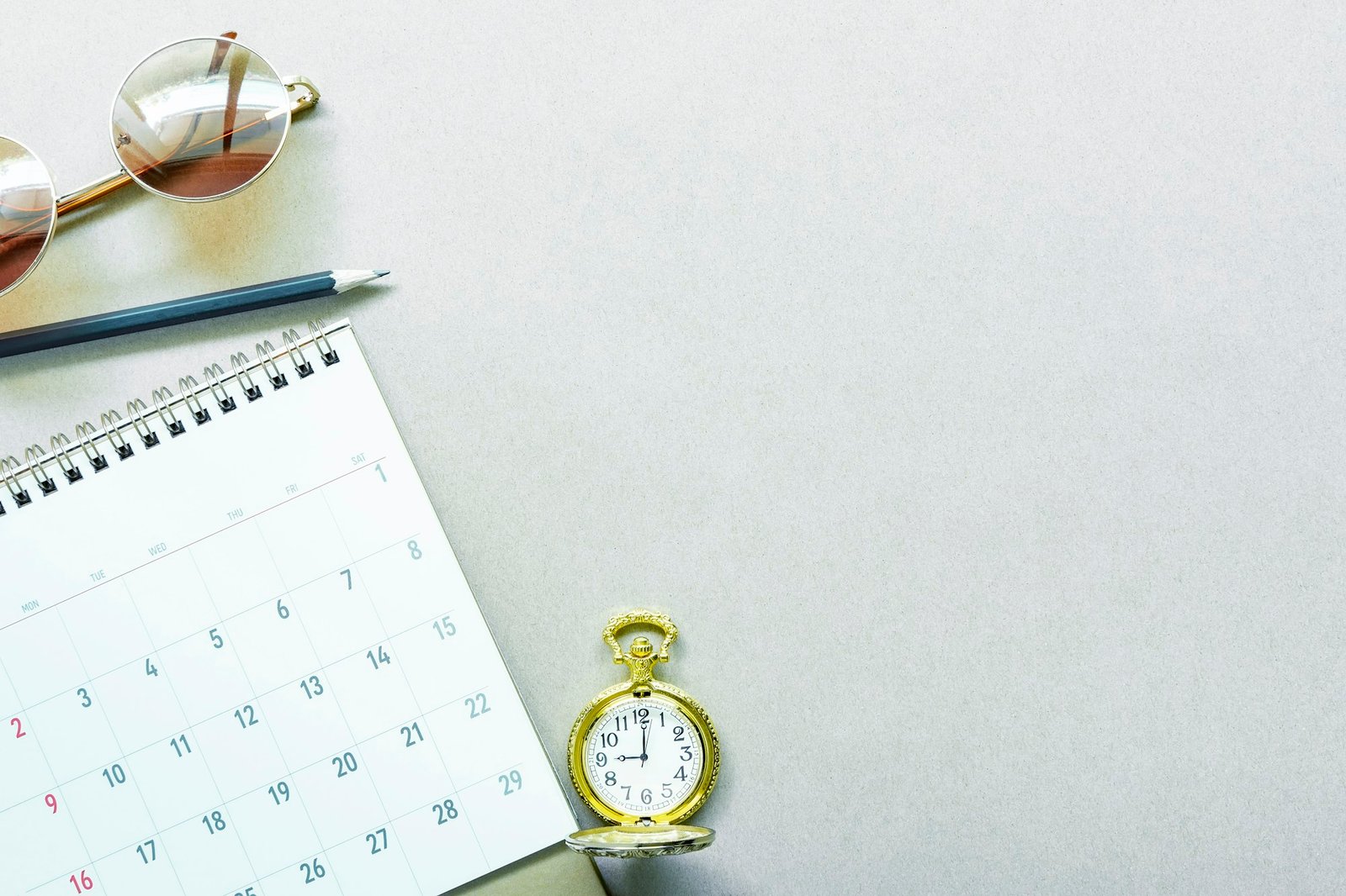 Work schedule and planning concept. Calendar, pencil, golden pocket watch and sunglasses on desk.